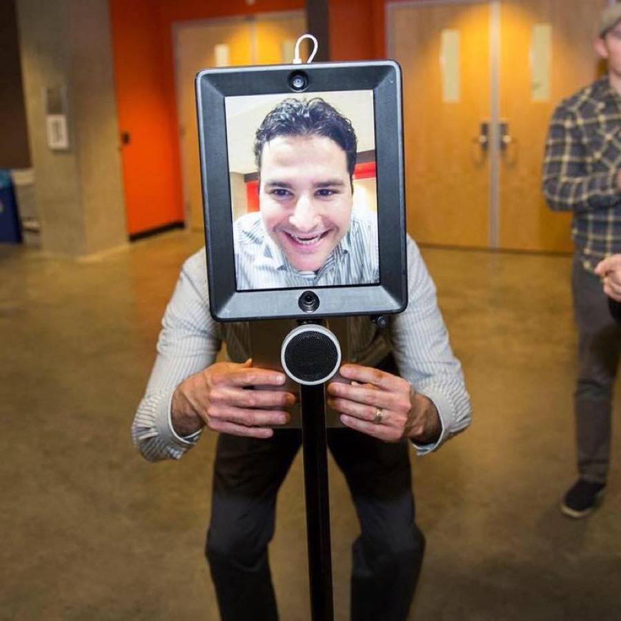 Christopher Campbell smiling on the screen of a telepresence robot at the Cronkite School